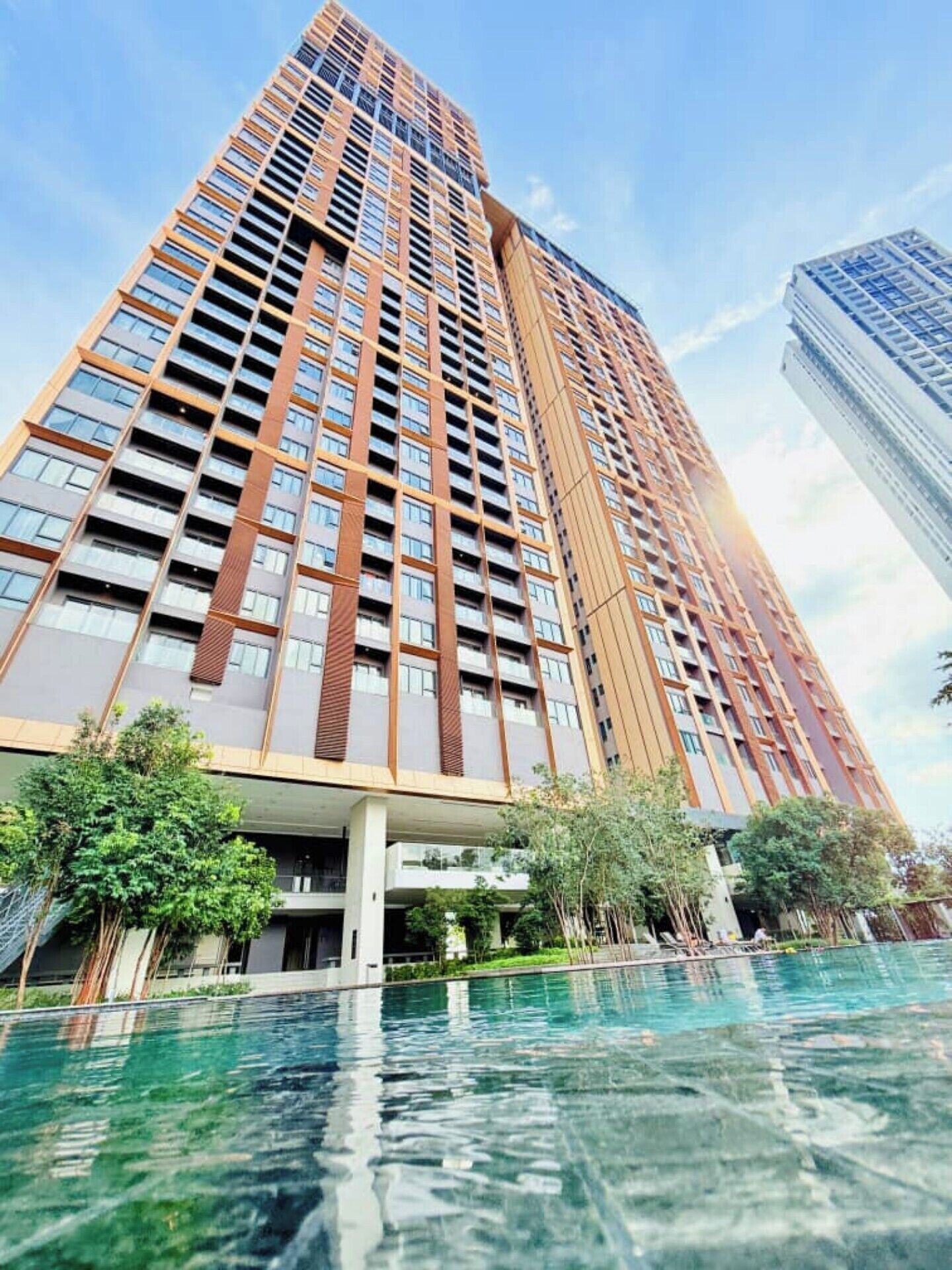 Un edificio alto con varios balcones y una piscina al frente.
