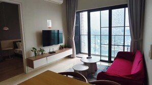 A modern living room with a flat-screen TV, a dining table, and a red chair.