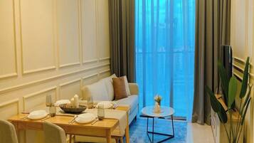 A modern living room with a dining area, a sofa, a coffee table, and a large window with curtains.