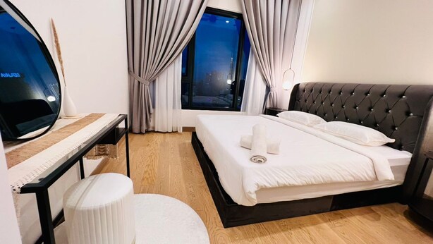 Une chambre d’hôtel comprenant un lit, un bureau, une chaise, une fenêtre avec des rideaux et un téléviseur.