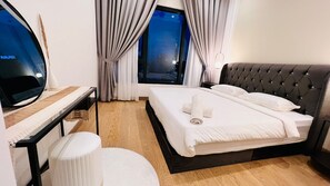 Ein Hotelzimmer mit Bett, Schreibtisch, Stuhl, einem Fenster mit Vorhängen und einem Fernseher.