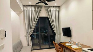 Un salon moderne comprenant un canapé, une table à manger, des chaises, un ventilateur de plafond et un téléviseur.