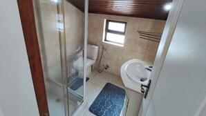 Une salle de bain comprenant des toilettes, un bidet, un lavabo et une petite fenêtre.