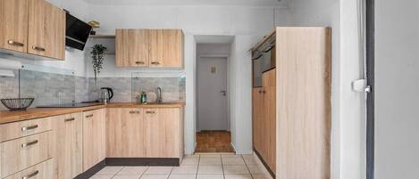 A modern kitchen with wooden cabinets, a tiled backsplash, and a black range hood.