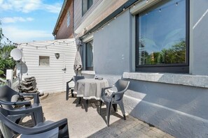 A patio with a table and chairs, a satellite dish, and a window with a view of greenery. - Brick-Lane by Loftigo - Patio & Sunroom (Selfkant)