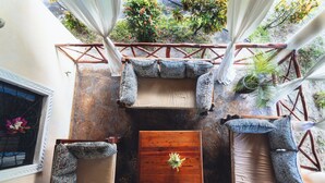 A rooftop terrace with a wooden table, two cushioned seating areas, and a view of greenery. - Relaxing 4-bedroom beach house at Malindi sand dunes perfect for family getaway (Mambrui)