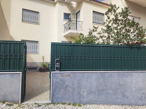 A gated entrance with a mailbox, a potted plant, and a building with a balcony. - Lisbon Airport GuestHouse Gal – Twin Bedroom (Lisbon)