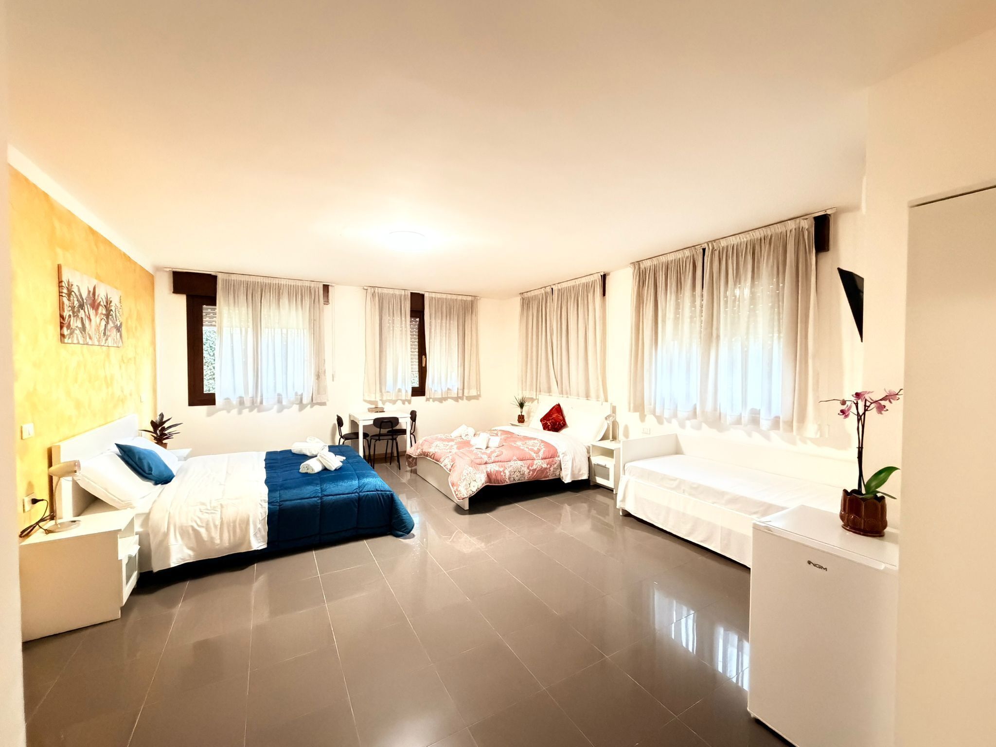 A modern hotel room with two beds, a desk, and a small refrigerator.