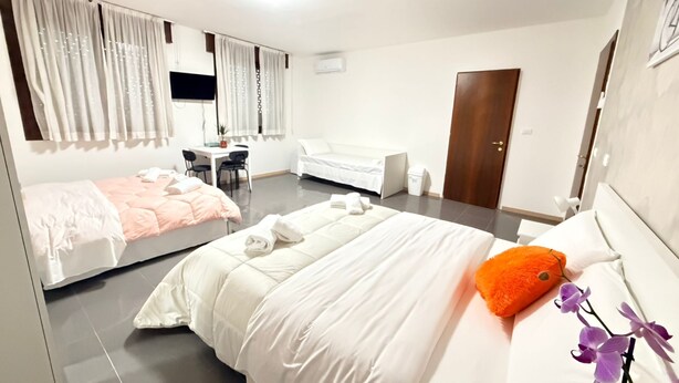 Habitación de hotel con dos camas, un escritorio, una silla, un armario y una puerta.