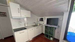 Een keuken met witte kastjes, een spoelbak, een fornuis en een glazen kastje in groen.