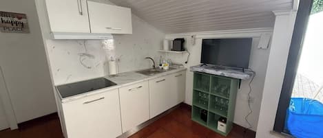 A kitchen with white cabinets, a sink, a stove, and a green glass cabinet.