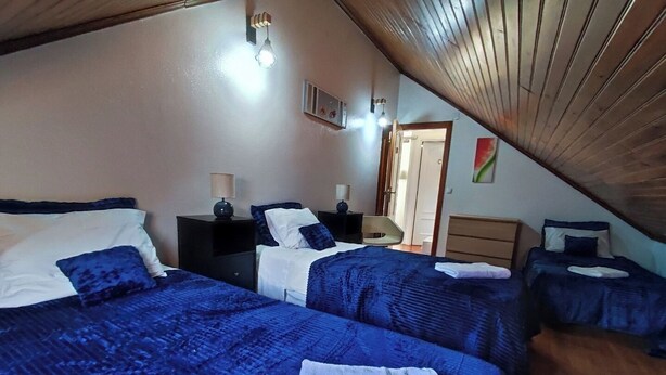 Ein Schlafzimmer mit zwei Betten, einem Nachttisch, einer Kommode und einem Deckenventilator.