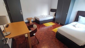 A hotel room with a bed, a desk, a chair, a wardrobe, and a small table. - Lisbon Airport GuestHouse Gal - Suite w/ Wc (Lisboa)