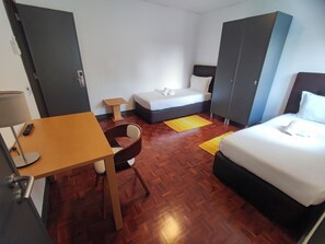 Ein Hotelzimmer mit Bett, Schreibtisch, Stuhl, Kleiderschrank und einem kleinen Tisch.