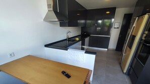 A modern kitchen with a wooden table, a black countertop, and stainless steel appliances. - Lisbon Airport GuestHouse Gal - Suite w/ Wc (Lisboa)