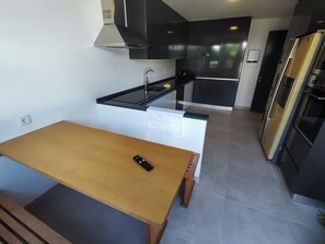 Eine moderne Küche mit Holztisch, schwarzer Arbeitsplatte und Edelstahlgeräten.