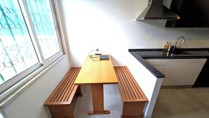 A kitchen with a wooden table and bench, a window with a view, and a sink with a bottle of dish soap. - Lisbon Airport GuestHouse Gal - Suite w/ Wc (Lisboa)
