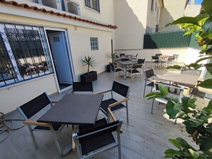 An outdoor patio with tables and chairs, a door, and a small plant. - Lisbon Airport GuestHouse Gal – Twin Bedroom (Lisbon)