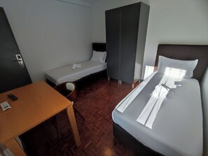 Une chambre d’hôtel comprenant un lit, un bureau, une armoire et un petit coin salon.