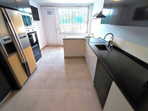 A compact kitchen with a refrigerator, oven, and sink. - Lisbon Airport GuestHouse Gal – Twin Bedroom (Lisbon)
