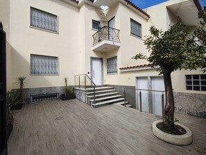 A multi-story building with a staircase leading to a balcony, potted plants, and a tree in the courtyard. - Lisbon Airport GuestHouse Gal – Twin Bedroom (Lisbon)
