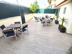 An outdoor patio with tables and chairs, a tree, and potted plants. - Lisbon Airport GuestHouse Gal – Twin Bedroom (Lisbon)