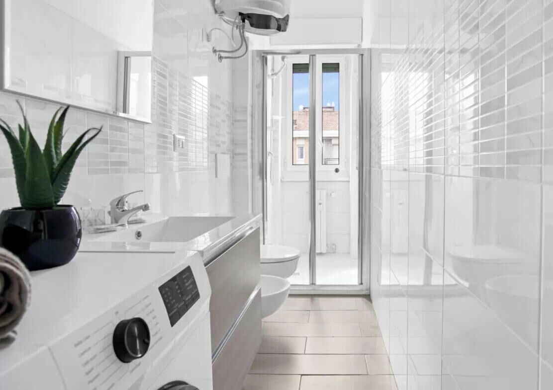 A modern bathroom with a large mirror, a sink, and a shower area.