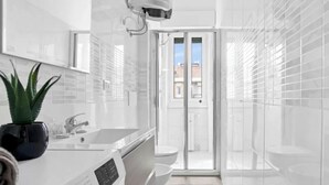 Un baño moderno con un espejo grande, un lavabo y una zona de ducha.