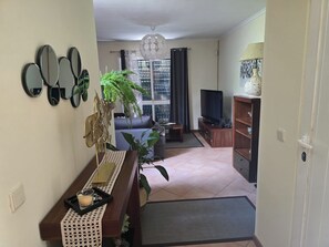 A living room with a sofa, TV, wooden sideboard, and decorative mirrors. - Madeira, 2 Bedroom Nature Retreat near Santa Cruz (Gaula)