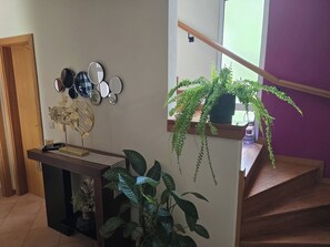 A staircase with a wooden handrail, a potted plant, and a wall-mounted mirror collection. - Madeira, 2 Bedroom Nature Retreat near Santa Cruz (Gaula)