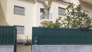 Uma entrada murada com uma caixa de correio, um vaso de planta e um edifício com varanda.