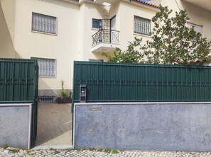 A gated entrance with a mailbox, a potted plant, and a building with a balcony. - Lisbon Airport GuestHouse Gal – Twin Bedroom (Lisbon)