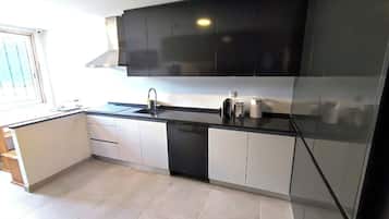 A modern kitchen with black cabinets, a sink, and a coffee maker.