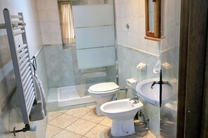 Une salle de bain comprenant une douche à parois de verre, des toilettes, un bidet et un lavabo.