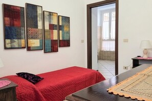Une pièce comprenant un lit, une table et trois œuvres d’art accrochées au mur.
