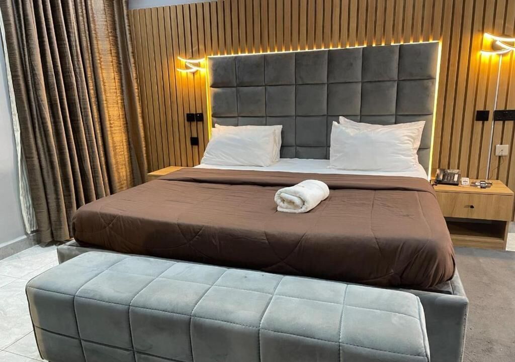Ein modernes Hotelzimmer mit einem großen Bett, zwei Nachttischen und einer Bank.