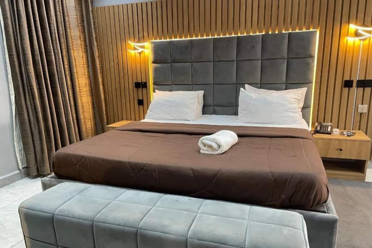 Ein modernes Hotelzimmer mit einem großen Bett, zwei Nachttischen und einer Bank.