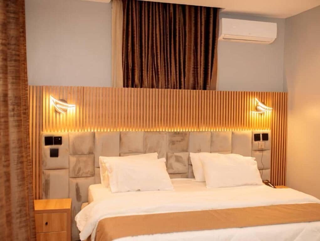 Une chambre d’hôtel avec un lit, des tables de chevet, un appareil de climatisation et un rideau.