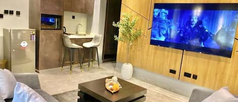 Ein modernes Wohnzimmer mit Flachbildfernseher, Couchtisch und Essbereich mit Stühlen.