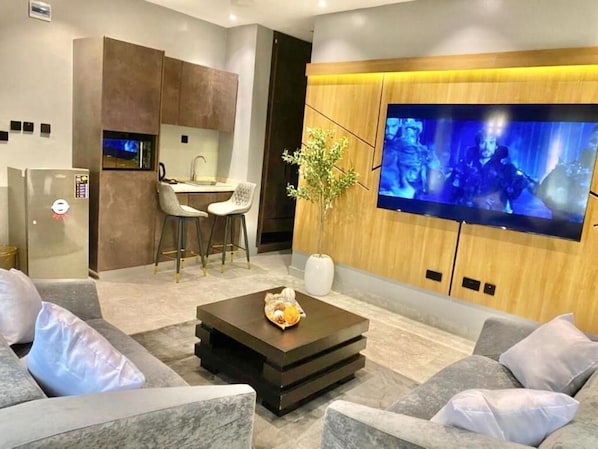Ein modernes Wohnzimmer mit Flachbildfernseher, Couchtisch und Essbereich mit Stühlen.