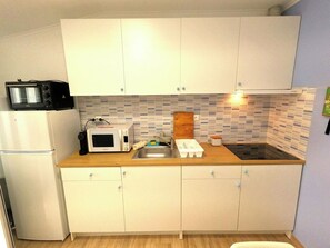 A compact kitchen with white cabinets, a microwave, a toaster, and a sink. - Cozy one-bedr. apartment in Costa da Caparica (Costa da Caparica)