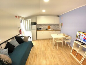A compact living space with a kitchenette, a dining area, and a television. - Cozy one-bedr. apartment in Costa da Caparica (Costa da Caparica)