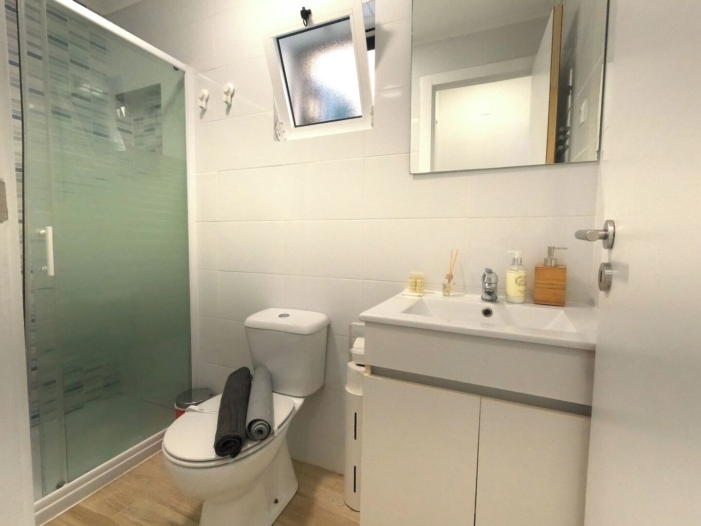 Une salle de bain comprenant des toilettes, une douche, un lavabo avec des articles de toilette et un miroir.