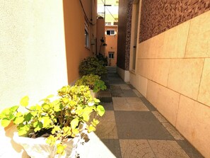 A narrow alleyway with a row of potted plants on one side and a building with a tiled wall on the other. - Cozy one-bedr. apartment in Costa da Caparica (Costa da Caparica)