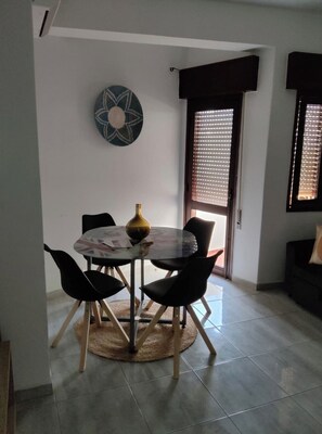 A dining area with a round table, four chairs, a vase, and a wall decoration. - Algarve, T1 Armação de Pêra near the Beach (Armação de Pêra)