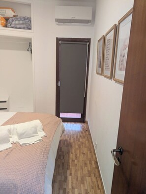 Quarto com cama, guarda-roupa, porta e ar condicionado fixado na parede.
