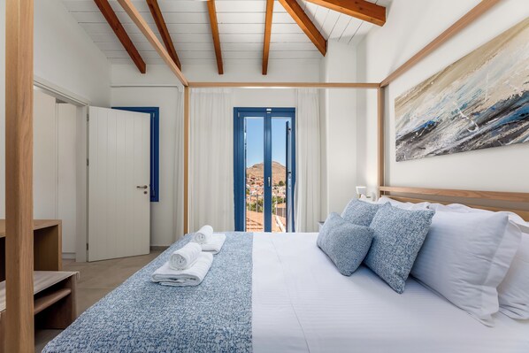 A hotel room with a bed, a view through a door, and a painting on the wall.
