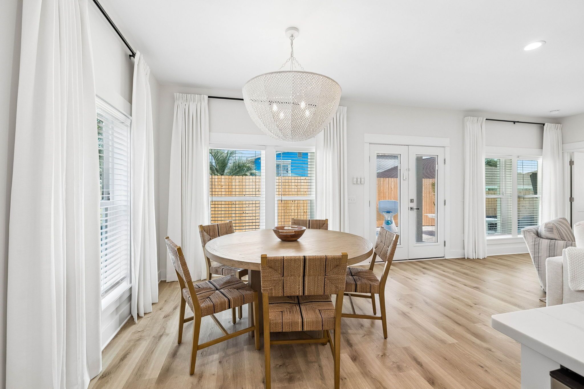 A dining area with a round table, chairs, and a chandelier.