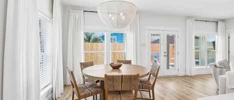A dining area with a round table, chairs, and a chandelier.