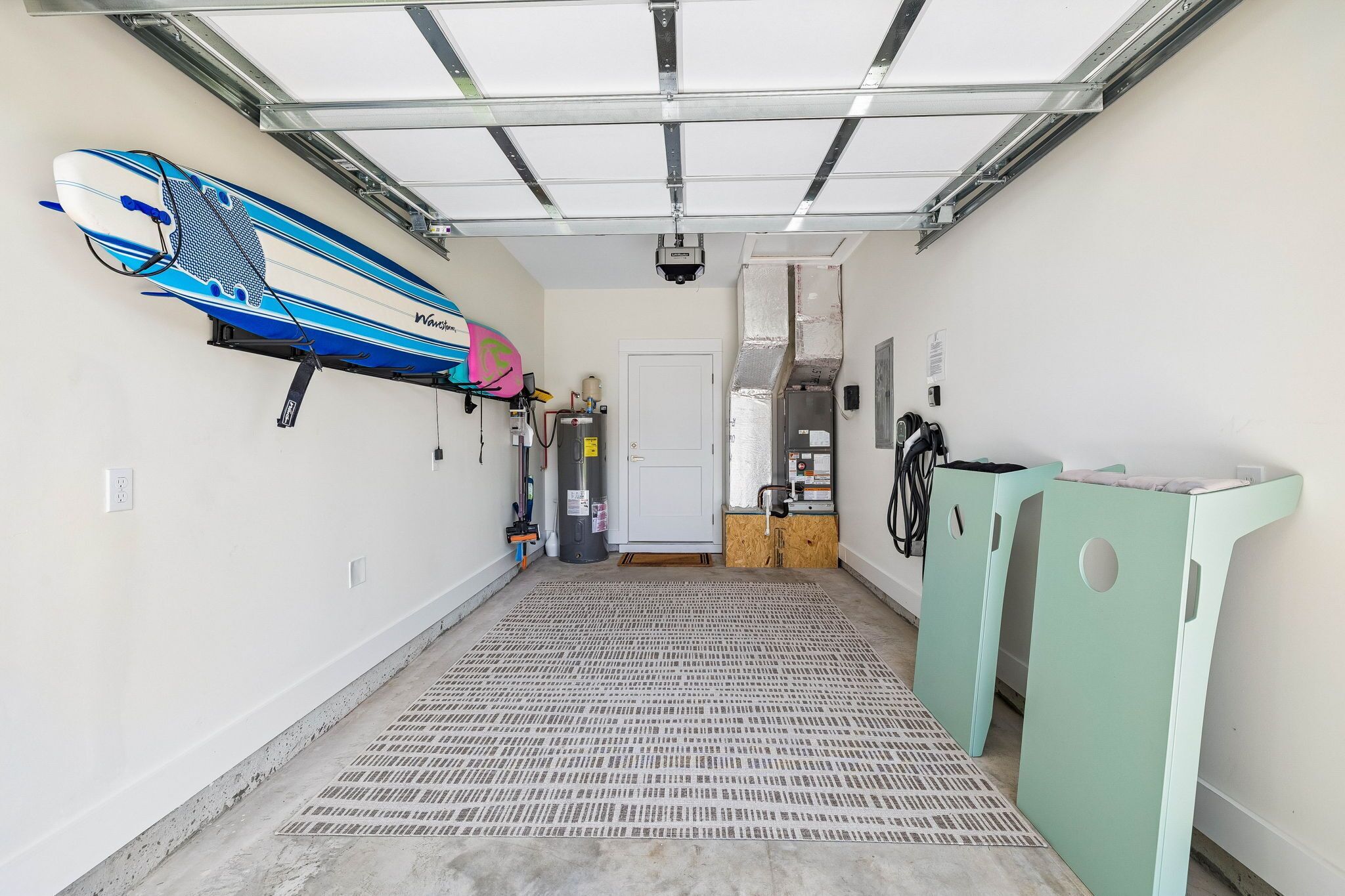 Uma garagem com suporte para pranchas de surf, aquecedor e um depósito verde.